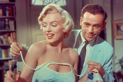 Tom Ewell le abrocha los tirantes a Marilyn Monroe
